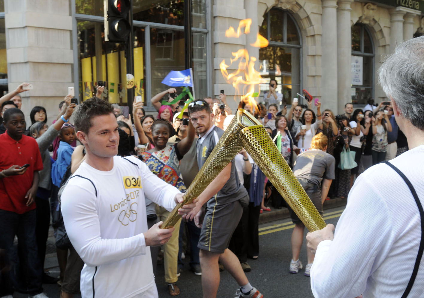 Enthusiastic crowds greet the Olympic Torch Relay as it passes through Islington in central London. The 'kissing point' as the flame passes from one torch to the next beofre the relay runner sets off.Â© Stefano Cagnoni - reportdigital.co.uk01789 262151 07831 121483info@reportdigital.co.ukwww.reportdigital.co.ukNUJ recommended terms & conditions apply. Moral rights asserted under Copyright Designs & Patents Act 1988. No part of this photo to be stored, reproduced, manipulated or transmitted by any means without permission.